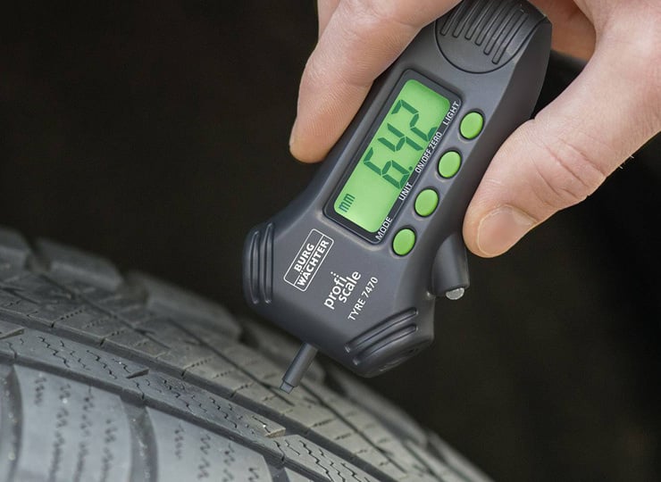 Une personne mesure la profondeur du profil d'un pneu