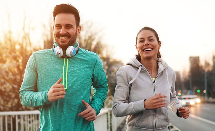Une femme et un homme font leur jogging en riant ensemble en plein air sur un pont dans la ville.