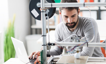 Un homme imprime une boule blanche avec une imprimante 3D.