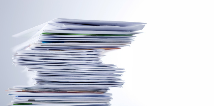 Une grande pile de nombreux documents en papier empilés de manière désordonnée.