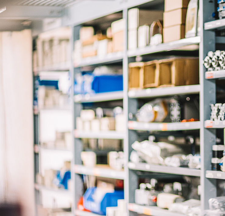 Plusieurs étagères dans un entrepôt sont remplies de différentes pièces de rechange et divers emballages.