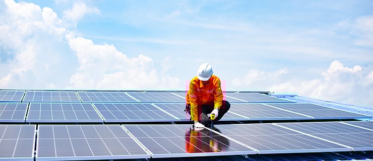 Un technicien installe des panneaux solaires sur un toit dans le cadre des technologies durables de bâtiment.