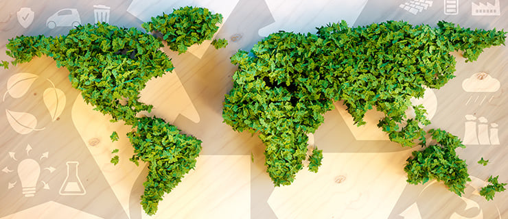 Carte du monde faite de feuilles vertes sur une table en bois avec des icônes numériques en arrière-plan.