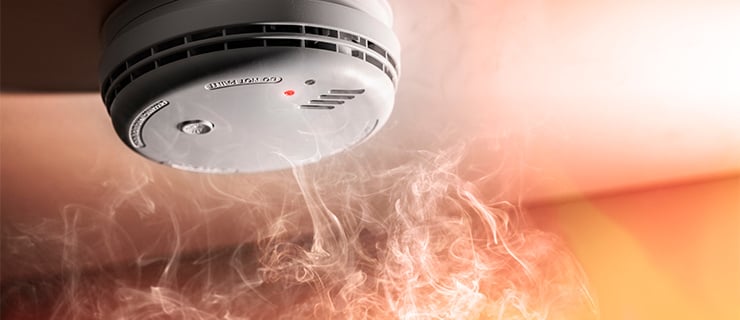 De la fumée s'élève vers un détecteur de fumée intelligent