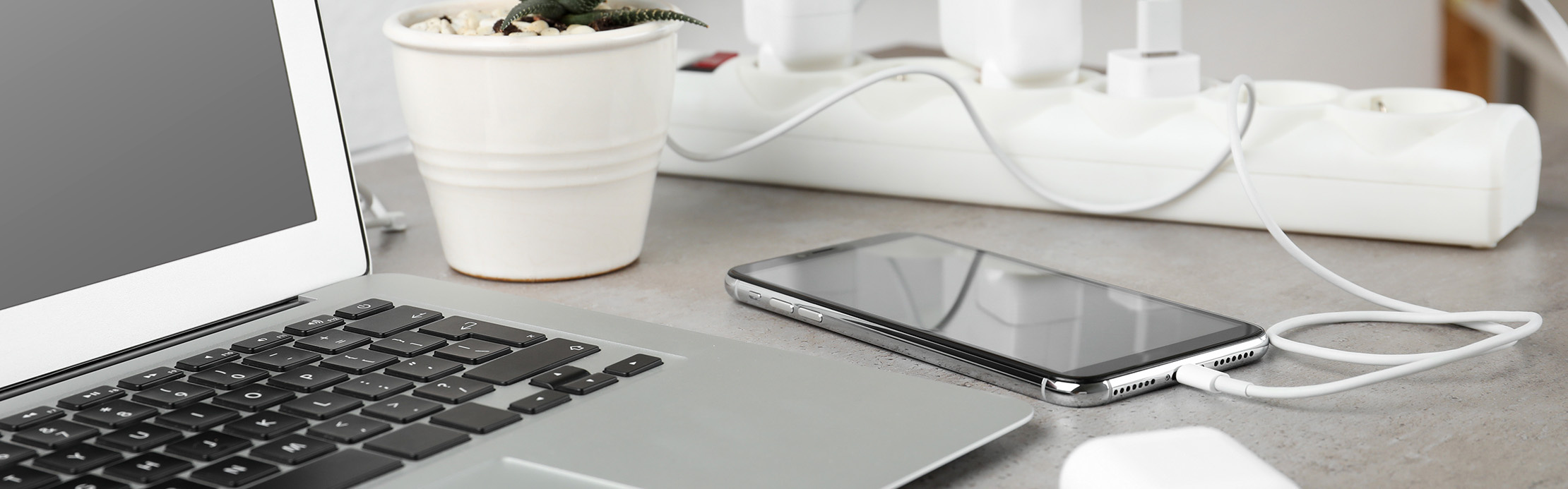 Le smartphone est alimenté via un câble de recharge, à côté d'un ordinateur portable