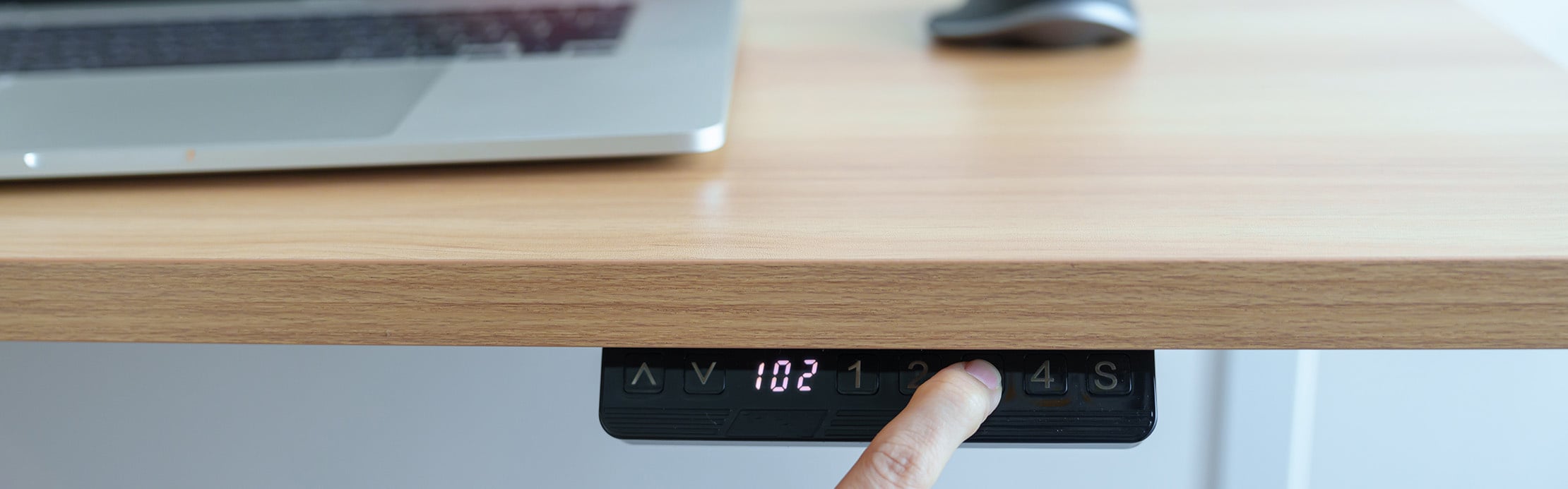 Une personne actionne la commande d'un bureau réglable en hauteur.